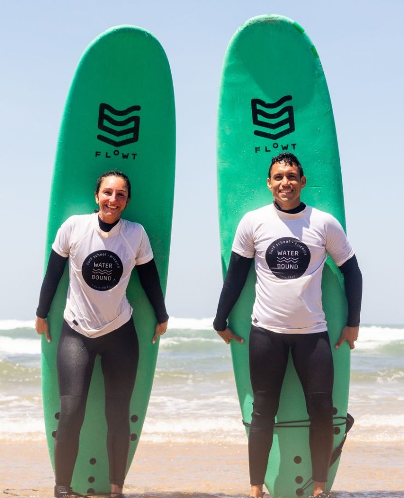 Two students after a private surf lesson in Ericeira, holding their Waterbound boards on the beach